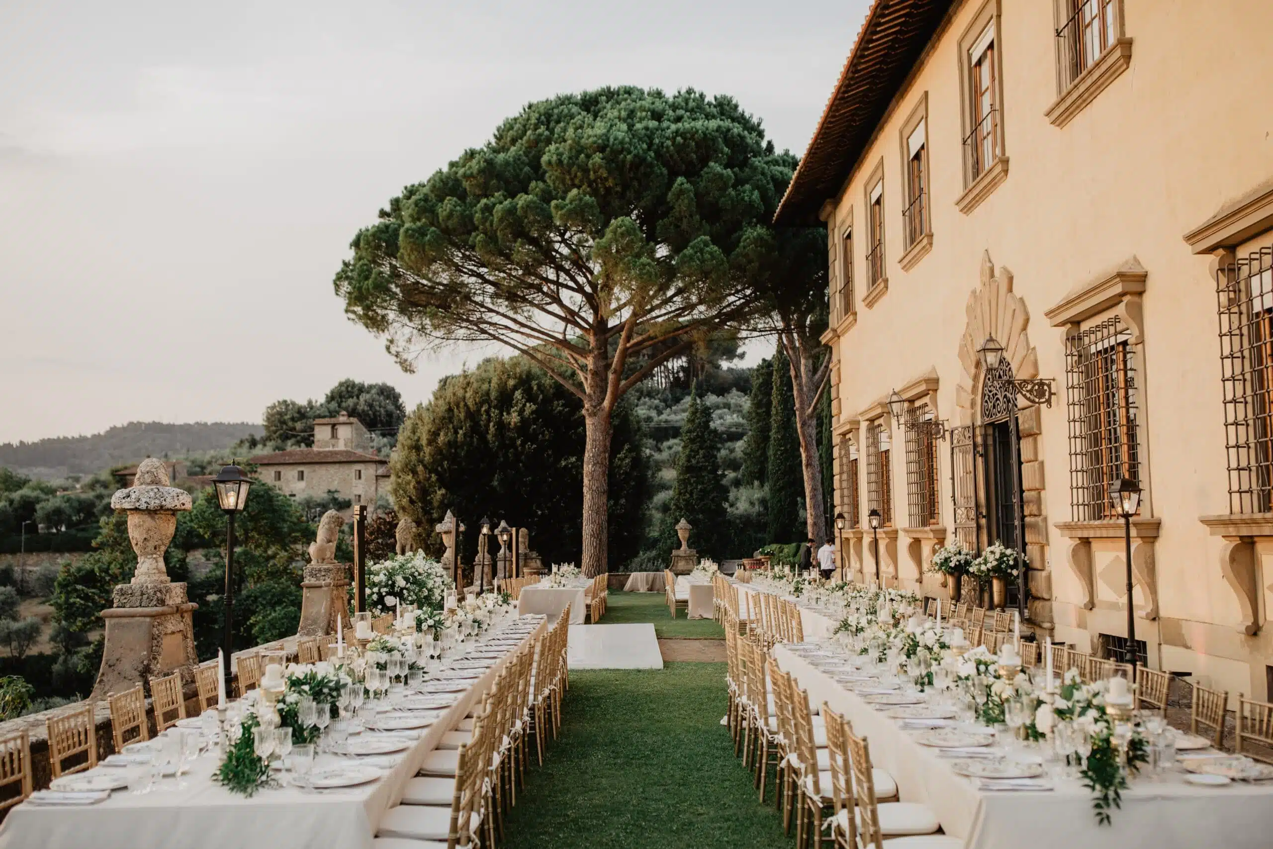 Outdoor wedding reception at sunset by an Italian lake with string lights and mountain backdrop
